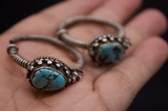 Silver ear ornaments. The hoops are made of pearled wire and the bezel is decorated with Turquoise. Excellent workmanship with a great patina for its age. This particular design is worn in pairs by women from Kham in East Tibet. These pieces might have been handed down to generations. *wear and tear as per age, intact. Weight: 28 grams Ring Size: 34mm Origin: Early 20th c Tibet Handmade Turquoise Jewelry For Ceremonial Occasions, Traditional Turquoise Metal Jewelry, Handmade Ceremonial Toe Ring Jewelry, Handmade Ceremonial Toe Ring, Traditional Hand Forged Jewelry As Gift, Traditional Hand Forged Jewelry For Gifts, Traditional Handmade Oval Jewelry, Traditional Hand Forged Jewelry Gift, Traditional Hand Forged Jewelry For Wedding