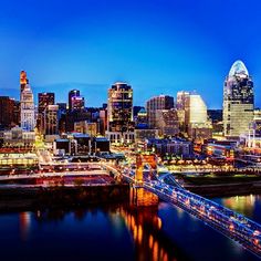 the city is lit up at night with lights on and bridges in front of it