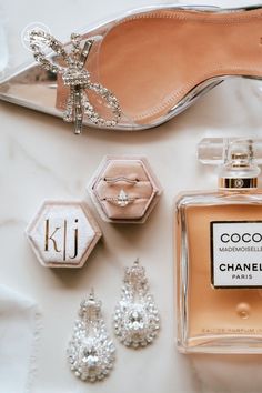 an assortment of women's accessories including shoes, perfume bottle and earrings on a white surface