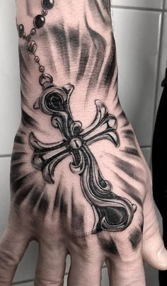 a person's hand with a cross tattoo on it and rosarys hanging from the wrist