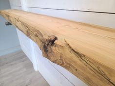 a close up of a wooden shelf on a white wall with wood flooring in the background