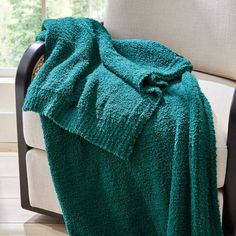 a green blanket sitting on top of a chair next to a window