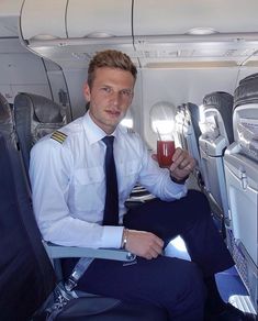 a man sitting on an airplane holding a drink