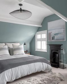 a large bed sitting under a window next to a fire place in a living room