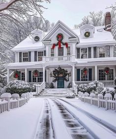 a large white house with wreaths on it's front door in the snow