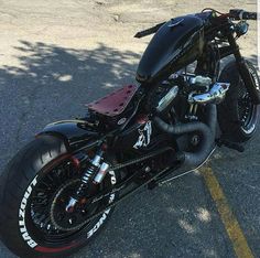 a black motorcycle parked in a parking lot next to a tree on the side of the road