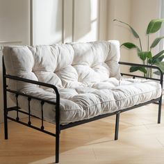 a white couch sitting on top of a hard wood floor next to a potted plant