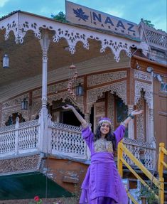 a woman standing in front of a building with her arms spread out and hands outstretched