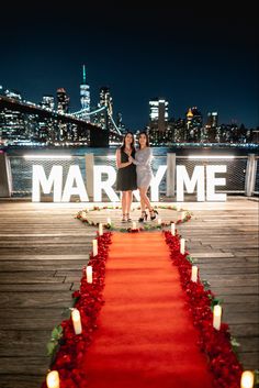 two women standing next to each other on a red carpet with candles in front of them