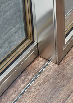 an open door on the side of a building with wood flooring and metal frame