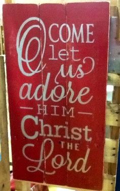 a red sign that says come let us adore him christ the lord on it