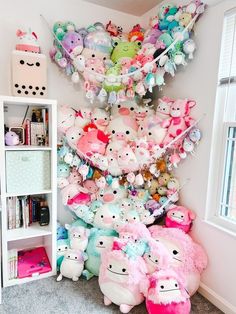 a room filled with lots of stuffed animals next to a bookshelf and window