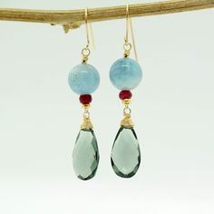 "Moss Aquamarine and Teal Quartz Earrings A stunning Teal-coloured Quartz Briolettes are dangling below large (10mm) Blue Moss Aquamarine beads accented with raspberry Ruby beads. The Briolette and The gems are wrapped with high quality 14k gold filled wire and swing from a gold filled hook. These are natural, not colourd excellent AAA quality gems, beautifuly faceted and sparkling. An elegant and feminine, chic statement earrings, perfect for special occasion, wedding, holidays or as a Gift for Aquamarine Drop Earrings With Ear Wire, Blue Drop Earrings With Ethical Gemstones, Elegant Aquamarine Earrings With Ear Wire, Handmade Elegant Aquamarine Earrings, Blue Gemstone Accented Drop Earrings, Blue Aquamarine Gemstone Earrings, Blue Drop Earrings With Gemstone Accents, Blue Drop Earrings With Natural Stones, Teal Jewelry