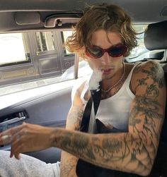 a man sitting in the back seat of a car with tattoos on his arms and shoulder