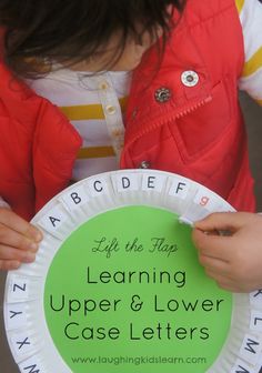 a child holding a paper plate with the words learning upper and lower case letters