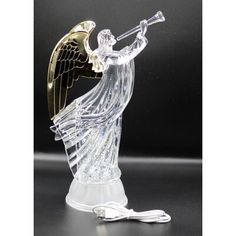 an angel figurine holding a trumpet on a black background with gold trimming