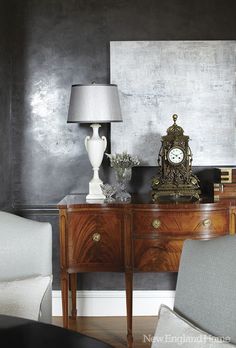 a living room with two chairs, a table and a clock on top of it