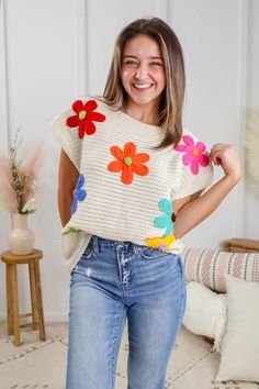 a woman wearing jeans and a sweater with flowers on it