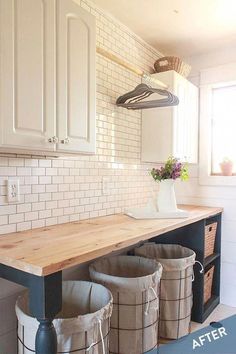 a kitchen with white cabinets and wooden counter top next to two trash canisters