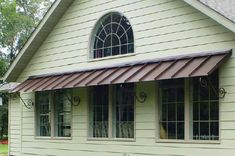 a white house with a brown awning on it's roof and two windows