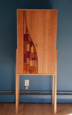 a wooden cabinet sitting on top of a hard wood floor next to a blue wall