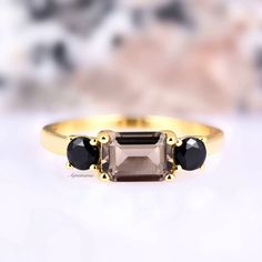 three stone ring on white surface with blurry background in the back ground and gold tone setting