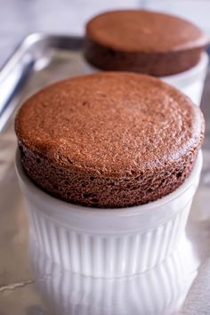 two chocolate cakes sitting on top of a metal tray