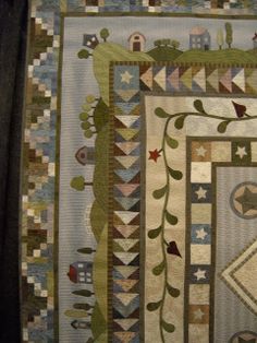 a close up of a quilt with many different designs on it, including trees and houses