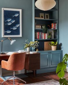 a home office with blue walls and wooden flooring, built in bookshelves