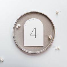 the number four is placed on top of a plate with flowers around it and scattered petals