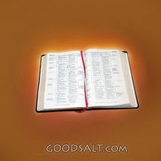 an open book sitting on top of a table next to a light that is turned on