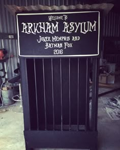 a sign that reads welcome to arkham asylm in front of a metal fence