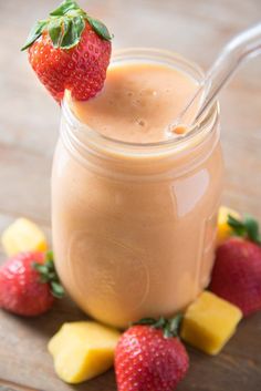 a glass jar filled with smoothie and strawberries