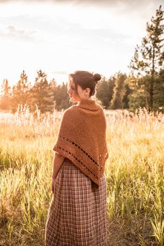 a woman standing in a field wearing a shawl