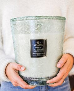 a woman holding a large glass container in her hands, with the lid open and she is wearing a white sweater