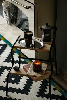 a small table with a candle on it in front of an oven and coffee pot