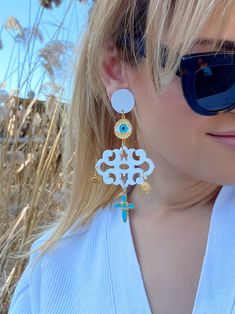 A unique pair of evil eye earrings that are made from plexiglass and metal parts in Gold, Turquoise and White colors with special pendant charms. They open and close with hypoallergenic clip on parts.  Find them only at  Christina Christi Store. DIMENSIONS - Total length of Long Earrings: 12 cm (4.72'') - Max Width 6 cm (0.98'') MATERIALS - Plexiglass Parts. - Metal Parts. - Clip On Earrings. PROTECTION - Protect them from water, perfumes, hair and body lotion to keep them bright and shiny for y White Spiritual Pierced Jewelry, White Spiritual Teardrop Earrings, Unique White Pierced Earrings, White Evil Eye Dangle Jewelry, White Spiritual Dangle Earrings, Spiritual White Dangle Earrings, Handmade White Dangle Plug Earrings, White Bohemian Jewelry With Dangling Charms, White Earrings With Dangling Charms For Gift