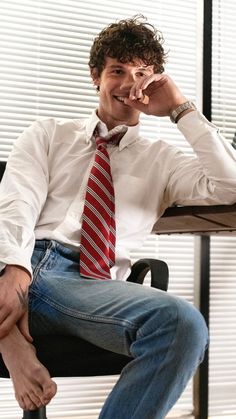 a man sitting in a chair with his feet up to his face while talking on the phone