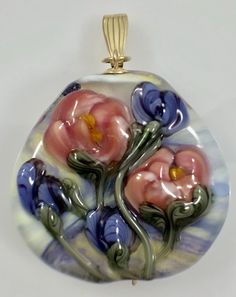 a glass pendant with pink and blue flowers on it