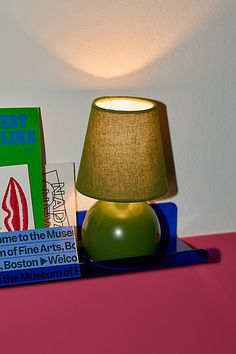 a green lamp sitting on top of a table next to some books and a box