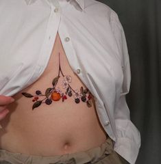 a woman's stomach with fruit and leaves tattoo on her belly, showing the lower side