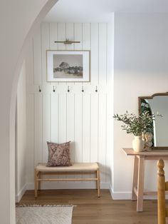 a bench and mirror in a room with white walls