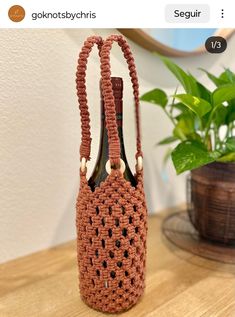 a crocheted bag sitting on top of a table next to a potted plant