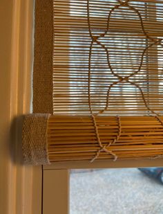 a cat is sitting on the window sill in front of the blinds that are made out of bamboo