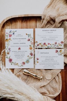 the wedding stationery is laid out on a wooden tray