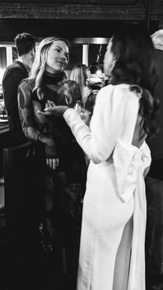 black and white photograph of two women in bathrobes talking to each other at a bar