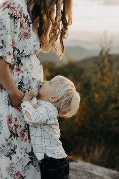 a mother and her toddler boy standing on top of a mountain