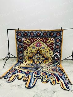 an intricately designed rug is displayed in front of a white wall and black metal frame