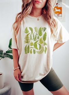 "Cottagecore Shirt | Botanical Shirt Women | Fern Shirt Women | Bluestar Fern | Lemon Button Fern | Crocodile Fern | I Love Ferns | Comfort Colors Shirt | Plant Mom Shirt Size Chart Available as the last image, The color in the main image is \"Ivory\"  Comfort Colors brand tees are a garment-dyed t-shirt, a fully customizable tee made 100% with ring-spun cotton. The soft-washed, garment-dyed fabric brings extra coziness to your wardrobe while the relaxed fit makes it an excellent daily choice. The double-needle stitching throughout the tee makes it highly durable while the lack of side-seams helps the shirt retain its tubular shape. - 100% ring-spun cotton - Medium fabric  - Relaxed fit - Sewn-in twill label PROCESSING TIME & SHIPPING: My products are made to order and they take 4-6 days o Green Graphic Tee With Plant Print, Green Graphic Tee With Plants Print, Spring Leaf Print Short Sleeve Tops, Green Short Sleeve Shirt With Plant Print, Short Sleeve Leaf Print Spring Top, Relaxed Fit Short Sleeve Shirt With Plant Print, Botanical Short Sleeve Graphic Shirt, Botanical Graphic Print Short Sleeve Shirt, Botanical Graphic Print Relaxed Fit Shirt