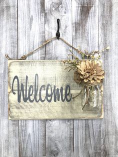 a welcome sign hanging on the side of a wooden fence with sunflowers and mason jars